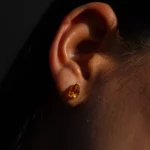 Gros plan d’une oreille portant une boucle d’oreille orange