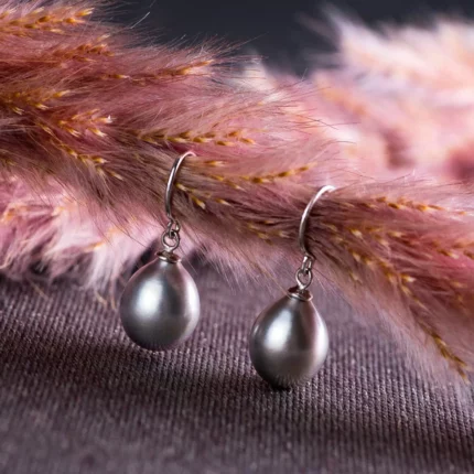 Boucles d’oreilles pendantes en perles grises sur tissu sombre