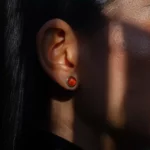 Gros plan d’une oreille avec une boucle d’oreille orange