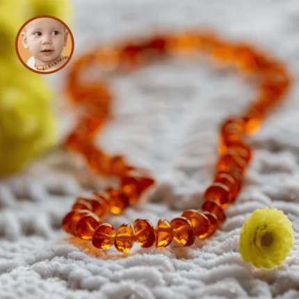 Collier d’ambre pour bébé sur couverture avec fleur jaune