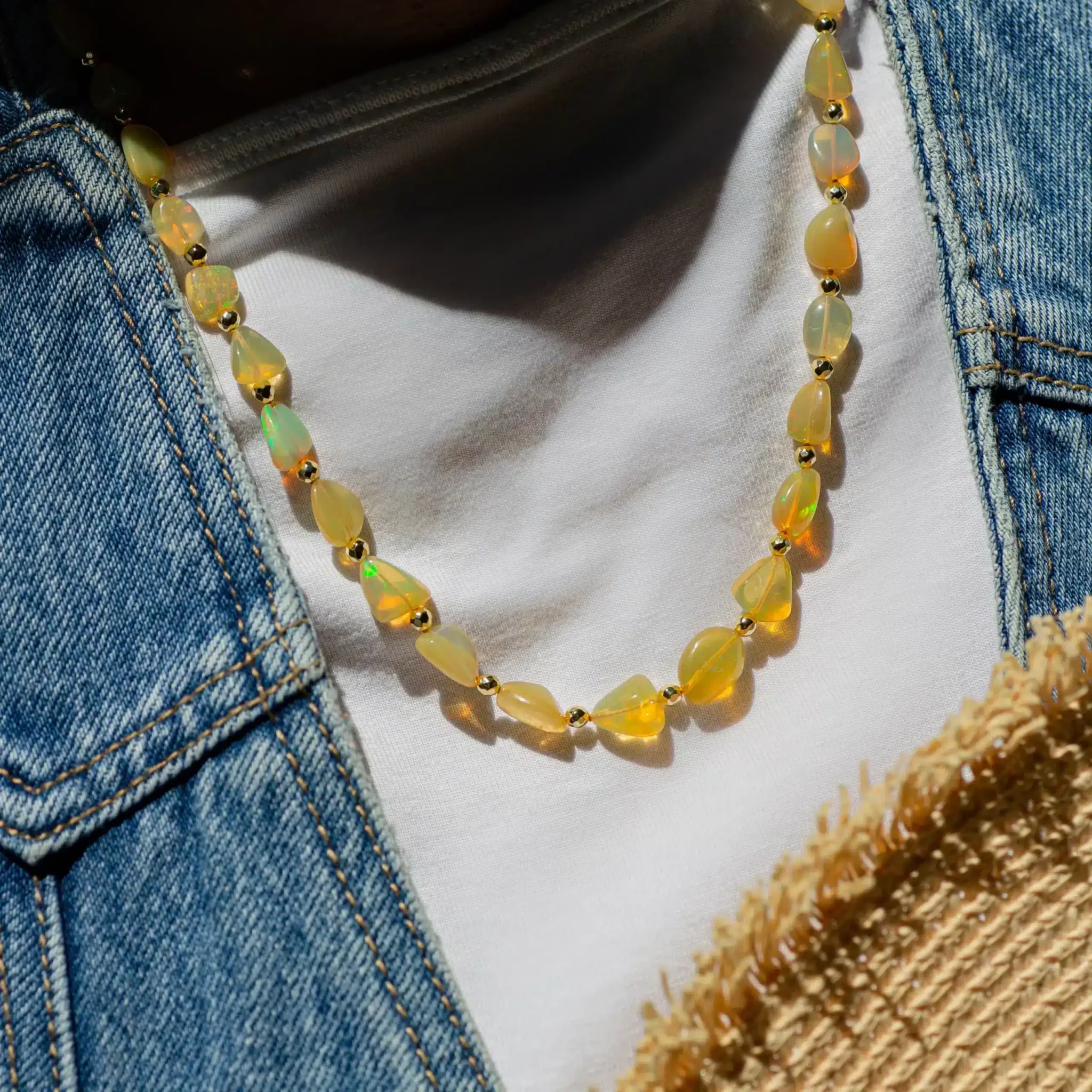 collier-opale-ethiopie-2-scaled-1.webp Collier de perles opalescentes sur t-shirt blanc et veste en jean