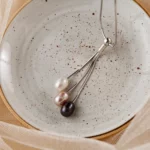 Collier argenté à trois perles sur assiette mouchetée