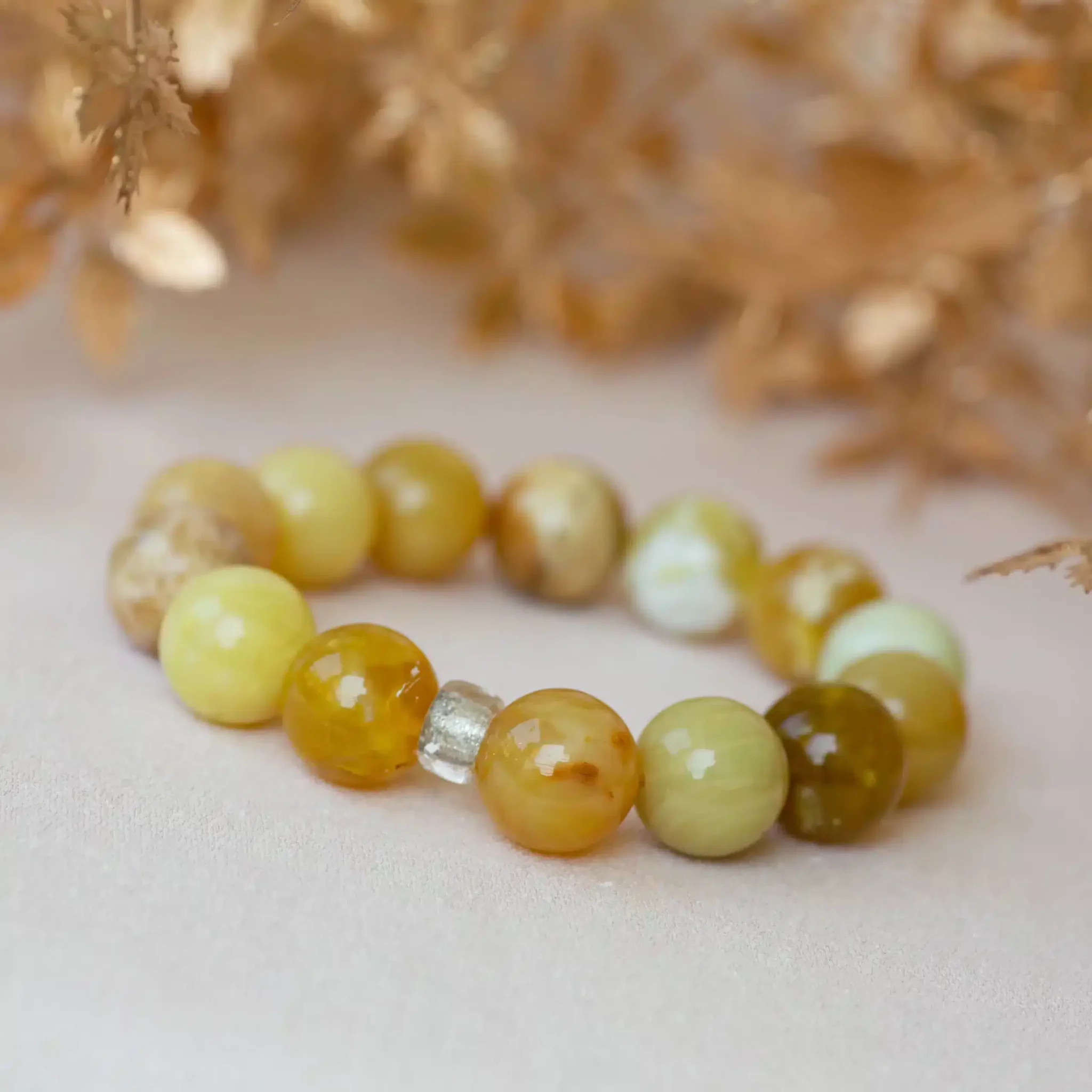 opale-jaune-bracelet2-scaled-1.webp Bracelet en perles jaunes et vertes sur tissu blanc