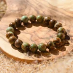 Bracelet de perles vertes et brunes sur tranche de bois