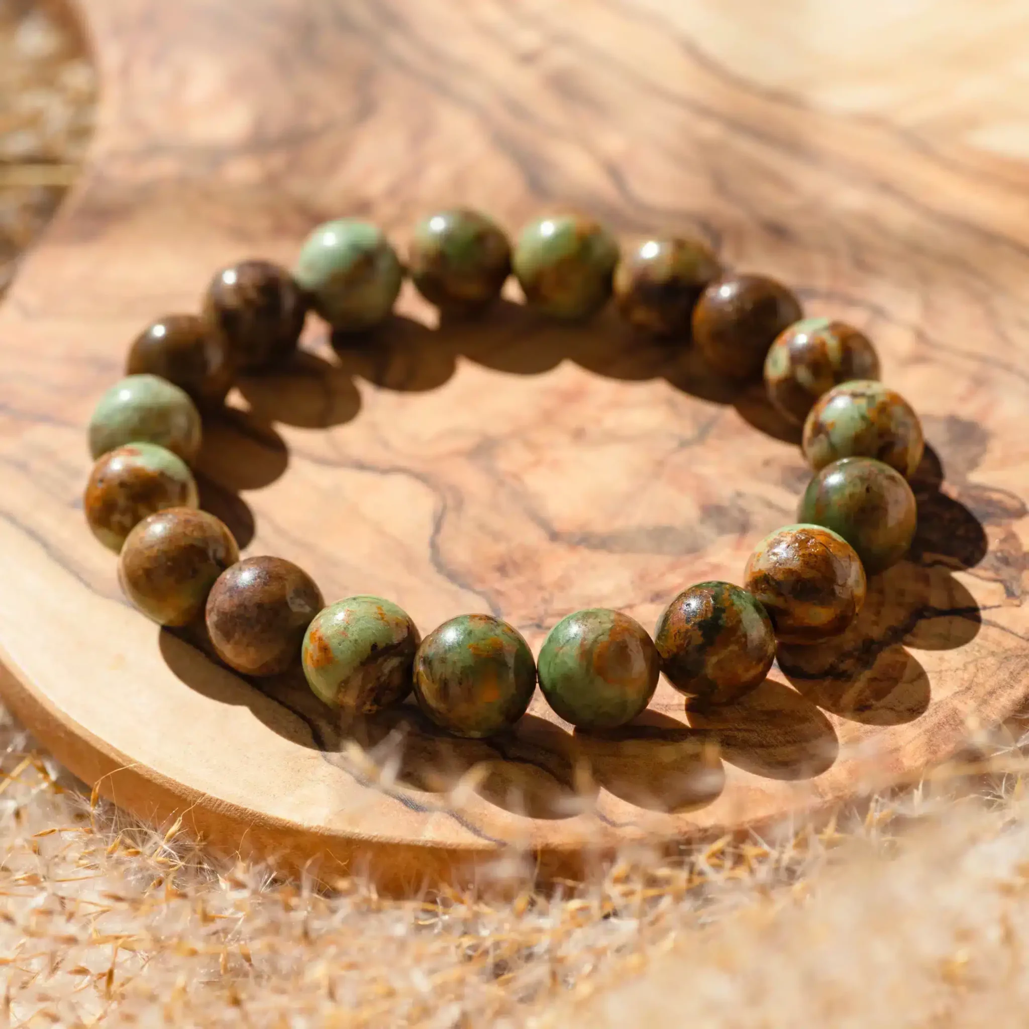 opale-pistache-10mm2-scaled-1.webp Bracelet de perles vertes et brunes sur tranche de bois