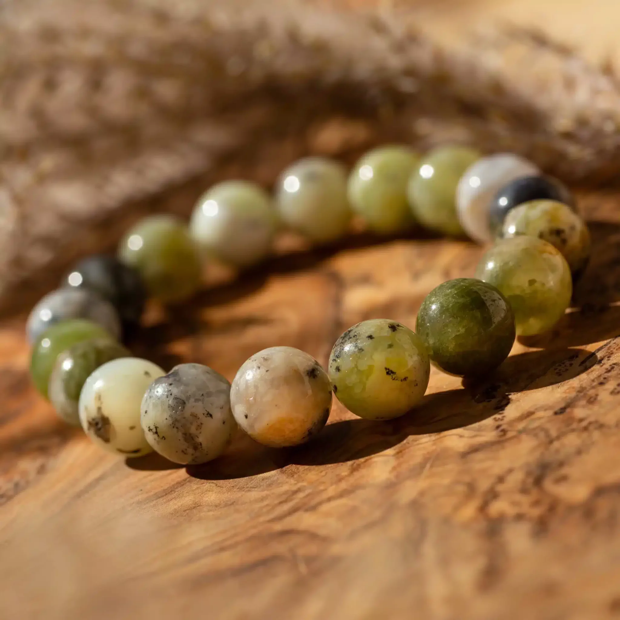 opale-verte-10mm4-scaled-1.webp Bracelet en perles vertes et blanches sur bois