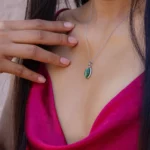Pendentif ovale vert sur chaîne argentée, porté au cou