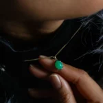 Main tenant pendentif doré avec pierre verte