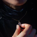 Personne tenant un pendentif rectangulaire en cristal sur chaîne dorée
